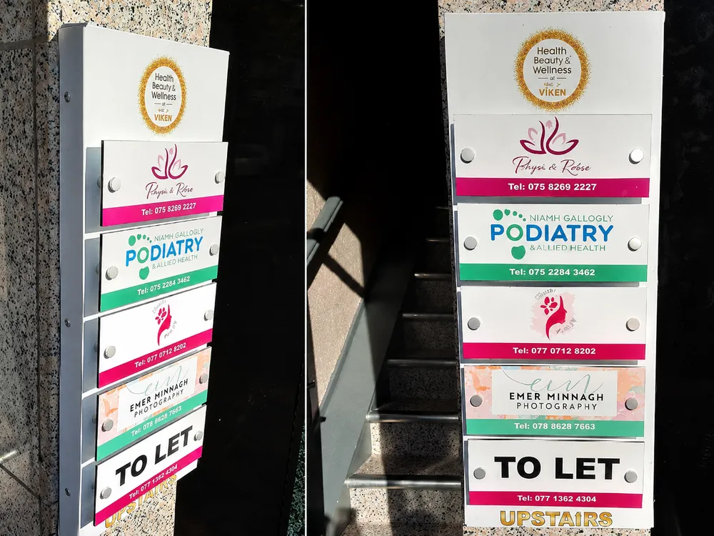 Stacked exterior building directory signs for several tenants, including Flower & Glow and a podiatry clinic.