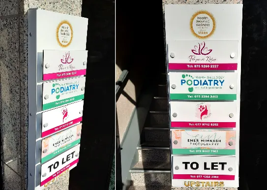 Stacked exterior building directory signs for several tenants, including Flower and Glow and a podiatry clinic.