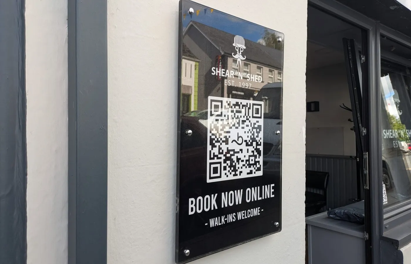 Black acrylic Shear 'n' Shed plaque with gold lettering and a QR code reading Book Now Online.