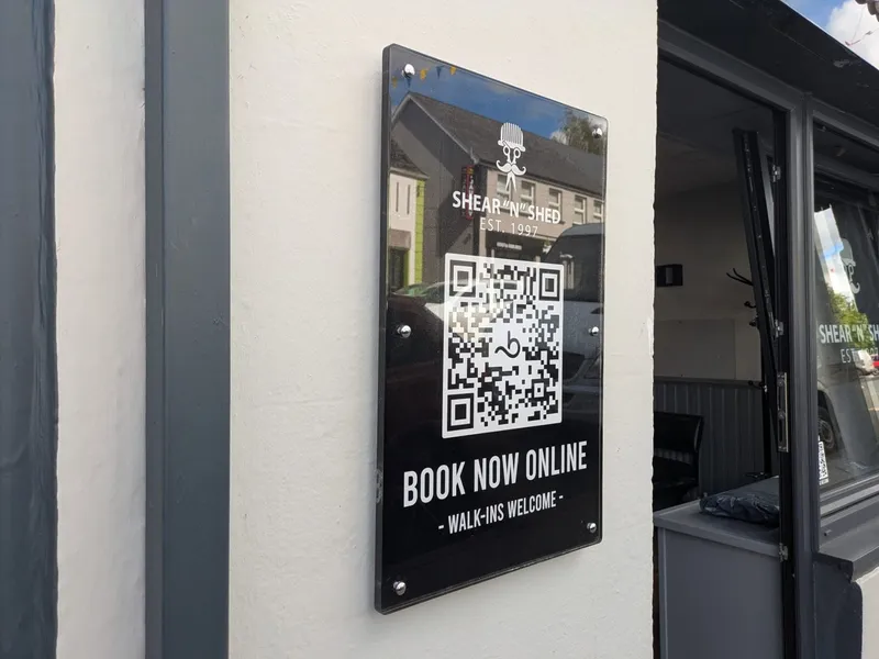 Black acrylic Shear 'n' Shed plaque with gold lettering and a QR code reading Book Now Online.